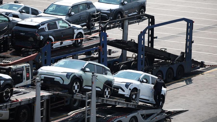 Sebuah pengangkut mobil yang mengangkut kendaraan buatan Kia Motors, yang merupakan bagian dari perusahaan pembuat mobil terbesar Korea Selatan, Hyundai Motor, melintasi pohon sakura yang sedang berbunga di dekat pelabuhan Pyeongtaek di Pyeongtaek, Korea Selatan, Selasa (15/4/2024). (REUTERS/Kim Hong-Ji)