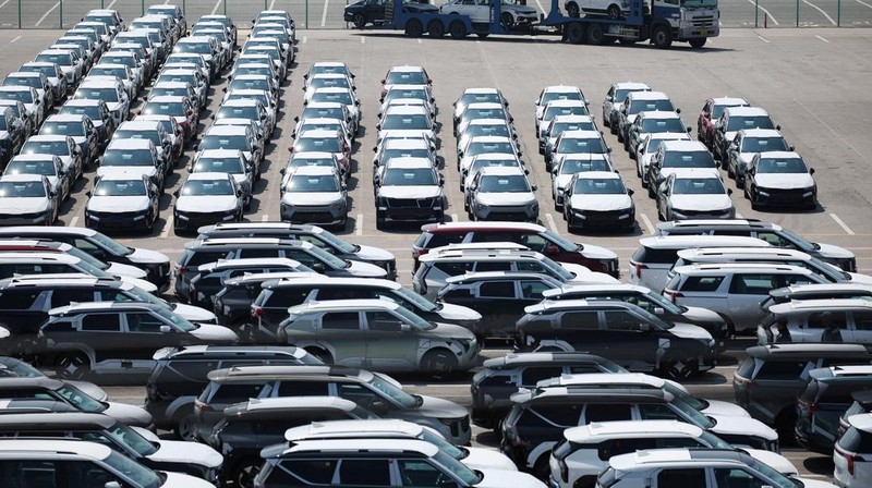 Sebuah pengangkut mobil yang mengangkut kendaraan buatan Kia Motors, yang merupakan bagian dari perusahaan pembuat mobil terbesar Korea Selatan, Hyundai Motor, melintasi pohon sakura yang sedang berbunga di dekat pelabuhan Pyeongtaek di Pyeongtaek, Korea Selatan, Selasa (15/4/2024). (REUTERS/Kim Hong-Ji)