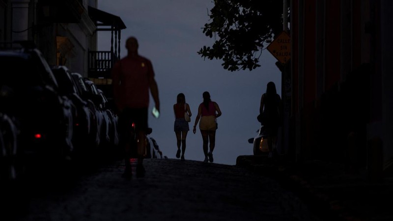 Orang-orang berjalan melalui jalan yang gelap setelah Puerto Riko dilanda pemadaman listrik besar-besaran di mana pembangkit listrik di seluruh pulau tiba-tiba mati, di San Juan, Puerto Riko, 16 April 2025. (REUTERS/Ricardo Arduengo)