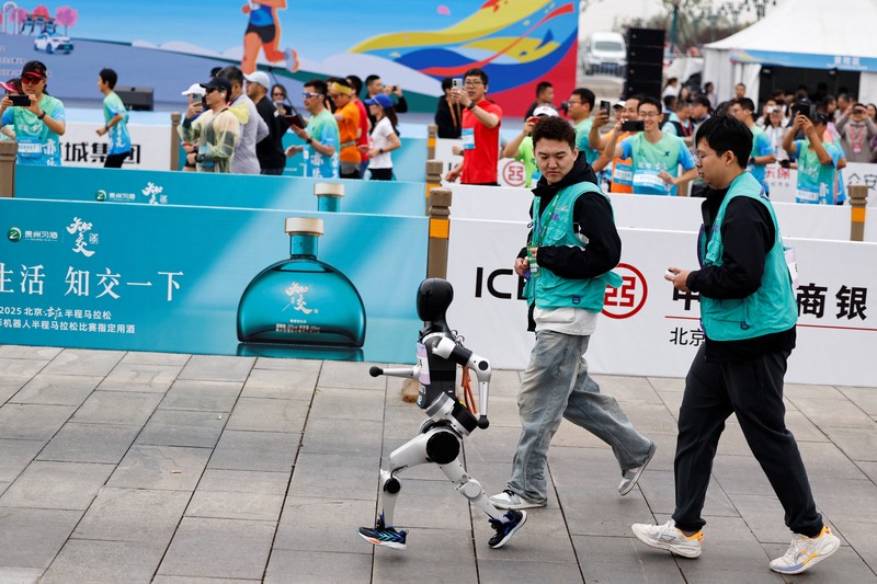 Para teknisi berlari bersama robot humanoid Para teknisi berlari bersama robot humanoid