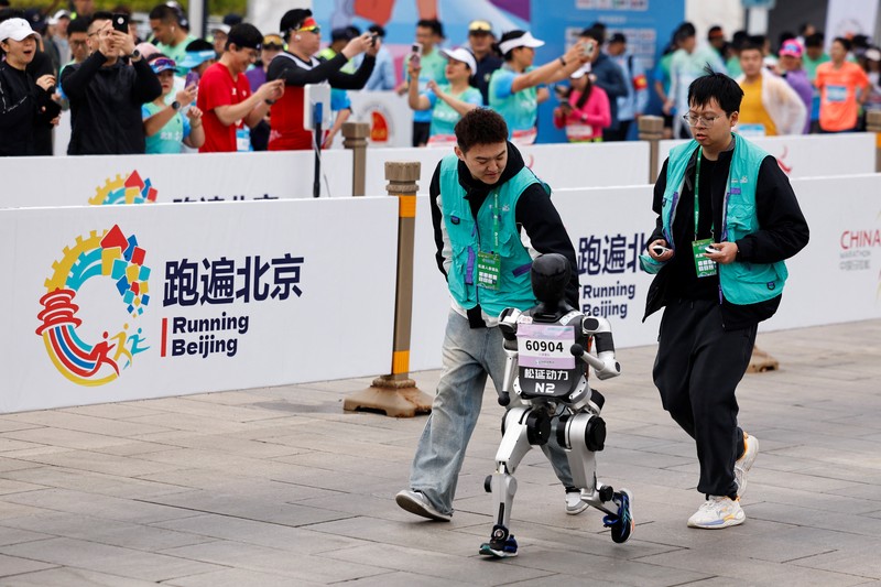 Para teknisi berlari bersama robot humanoid 