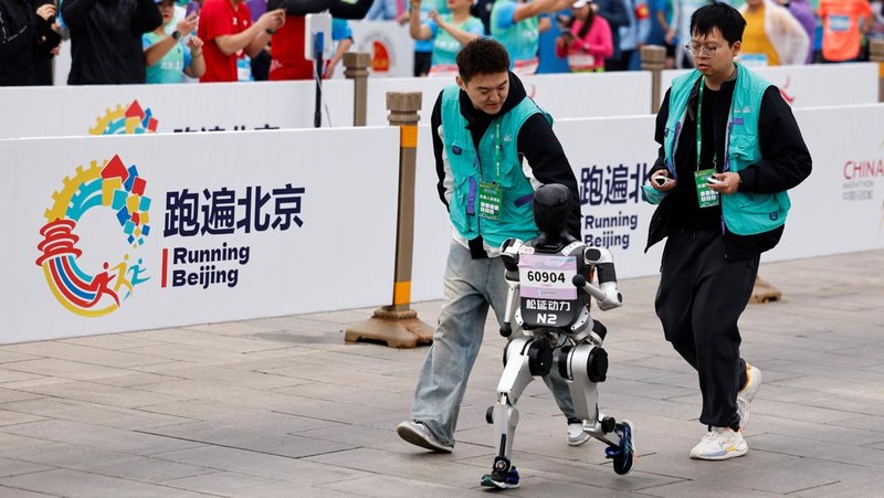 Para teknisi berlari bersama robot humanoid 