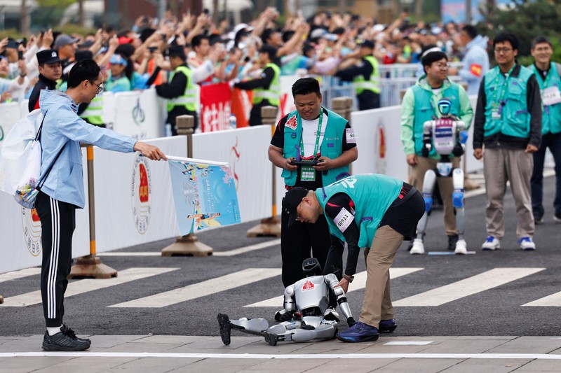 Para teknisi berlari bersama robot humanoid 