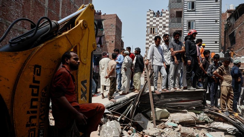 Petugas darurat menggunakan derek untuk memindahkan lempengan di lokasi bangunan runtuh di New Delhi, India, 19 April 2025. (REUTERS/Adnan Abidi)