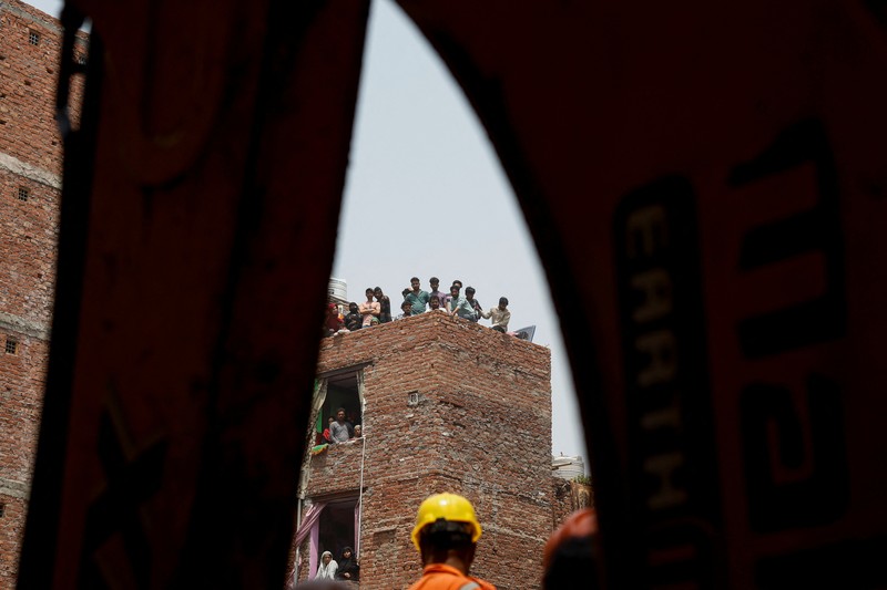 Petugas darurat menggunakan derek untuk memindahkan lempengan di lokasi bangunan runtuh di New Delhi, India, 19 April 2025. (REUTERS/Adnan Abidi)