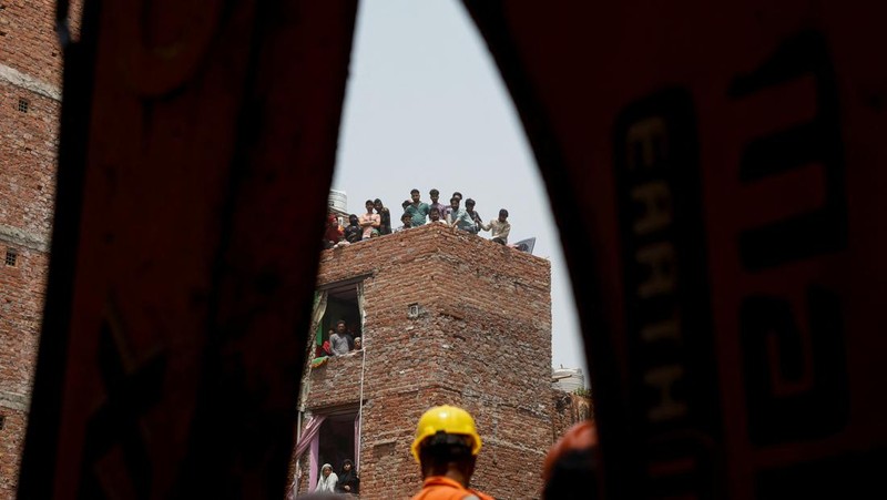 Petugas darurat menggunakan derek untuk memindahkan lempengan di lokasi bangunan runtuh di New Delhi, India, 19 April 2025. (REUTERS/Adnan Abidi)