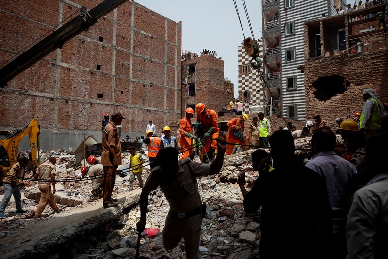 Petugas darurat menggunakan derek untuk memindahkan lempengan di lokasi bangunan runtuh di New Delhi, India, 19 April 2025. (REUTERS/Adnan Abidi)