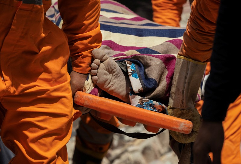 Petugas darurat menggunakan derek untuk memindahkan lempengan di lokasi bangunan runtuh di New Delhi, India, 19 April 2025. (REUTERS/Adnan Abidi)