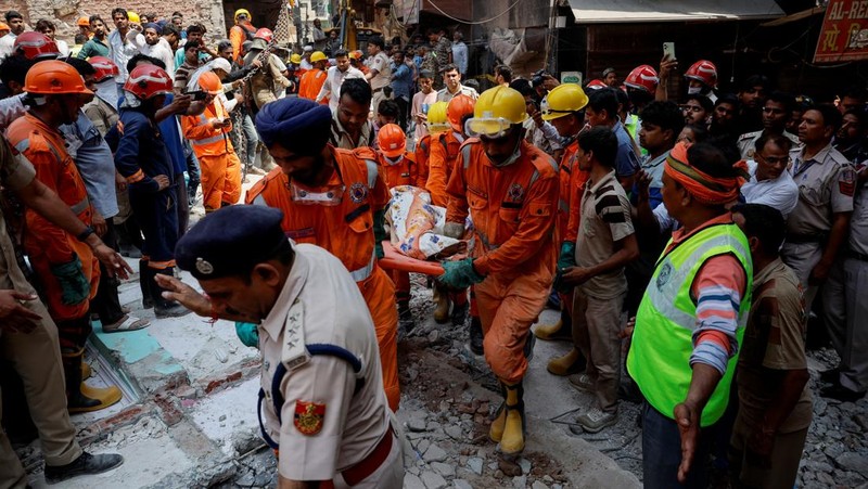 Petugas darurat menggunakan derek untuk memindahkan lempengan di lokasi bangunan runtuh di New Delhi, India, 19 April 2025. (REUTERS/Adnan Abidi)