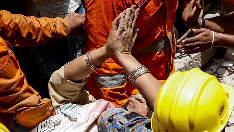 Petugas darurat menggunakan derek untuk memindahkan lempengan di lokasi bangunan runtuh di New Delhi, India, 19 April 2025. (REUTERS/Adnan Abidi)