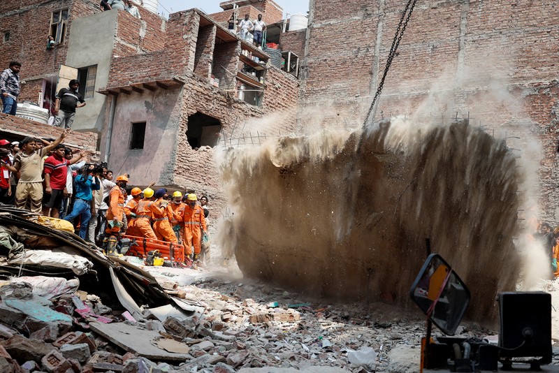 Petugas darurat menggunakan derek untuk memindahkan lempengan di lokasi bangunan runtuh di New Delhi, India, 19 April 2025. (REUTERS/Adnan Abidi)