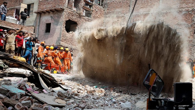 Petugas darurat menggunakan derek untuk memindahkan lempengan di lokasi bangunan runtuh di New Delhi, India, 19 April 2025. (REUTERS/Adnan Abidi)