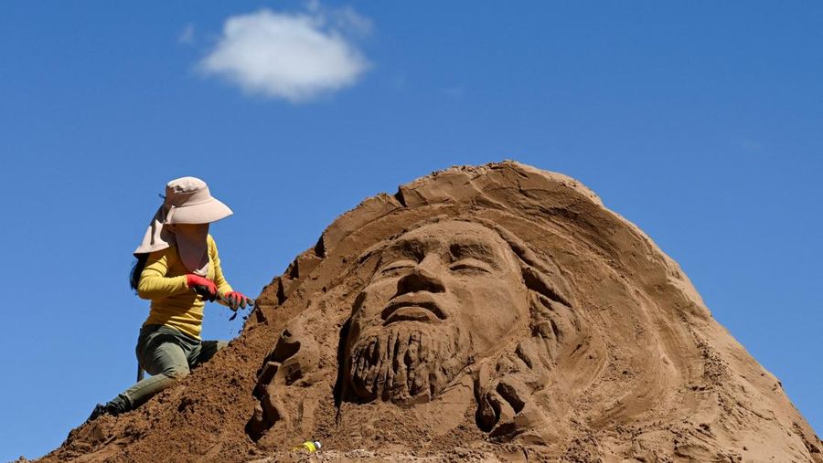 Seorang seniman visual memahat patung pasir berbentuk Yesus selama perayaan Pekan Suci di Arenales de Cochiraya, di pinggiran Oruro, Bolivia, 18 April 2025. (REUTERS/Claudia Morales)
