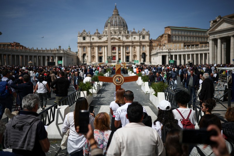 A pilgrim carries a cross near St Peter's square, after the death of Pope Francis was announced by the Vatican, as seen from Rome, Italy, April 21, 2025. REUTERS/Guglielmo Mangiapane