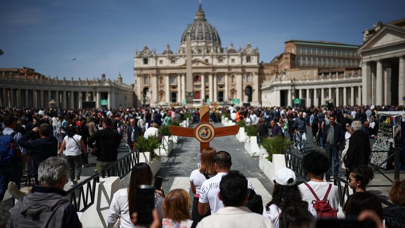 A pilgrim carries a cross near St Peter's square, after the death of Pope Francis was announced by the Vatican, as seen from Rome, Italy, April 21, 2025. REUTERS/Guglielmo Mangiapane