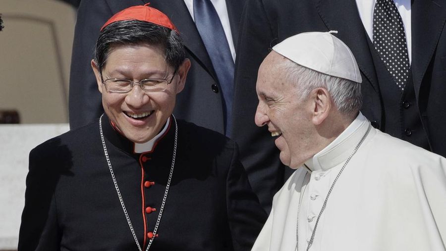 FILE - Pope Francis greets Cardinal Luis Antonio Tagle, archbishop of Manila, second from right, and group of migrants, during his weekly general audience, at the Vatican, Wednesday, Sept. 27, 2017. (AP Photo/Andrew Medichini, File)