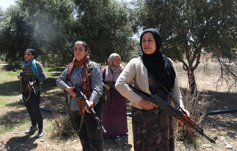 Wanita dan pria Kurdi menghadiri pelatihan tentang cara menggunakan senjata di Qamishli, Suriah, 12 April 2025. (REUTERS/Orhan Qereman)