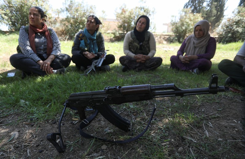 Wanita dan pria Kurdi menghadiri pelatihan tentang cara menggunakan senjata di Qamishli, Suriah, 12 April 2025. (REUTERS/Orhan Qereman)
