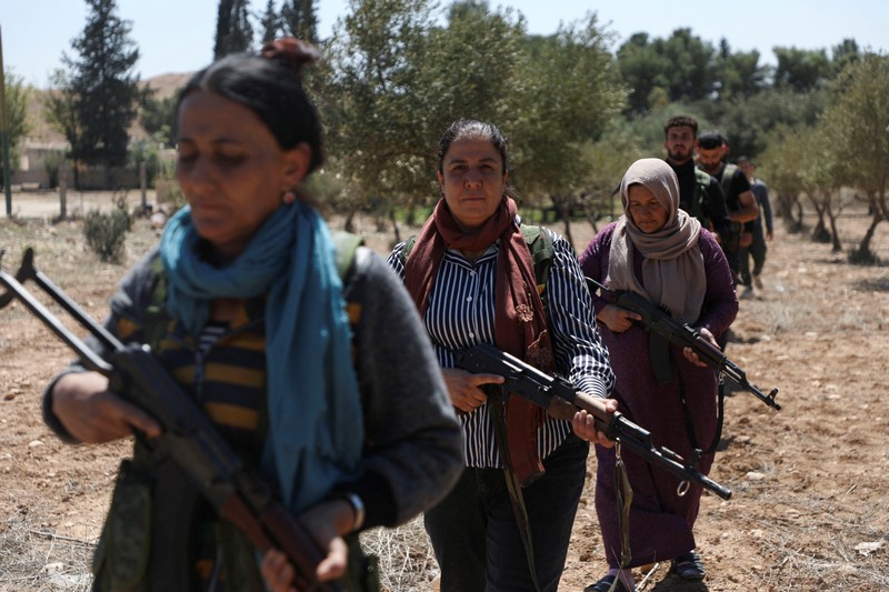 Wanita dan pria Kurdi menghadiri pelatihan tentang cara menggunakan senjata di Qamishli, Suriah, 12 April 2025. (REUTERS/Orhan Qereman)