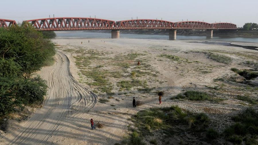 Orang-orang berjalan di dasar sungai kering Sungai Indus di Hyderabad, Pakistan, 24 April 2025. (REUTERS/Yasir Rajput)