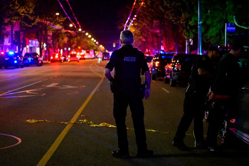 Petugas polisi bekerja di tempat kejadian perkara, sementara jasad korban tergeletak di tanah, setelah sebuah kendaraan melaju ke arah kerumunan saat pesta blok Lapu Lapu di Vancouver, Kanada, Sabtu (26/4/2025). (REUTERS/Chris Helgren)