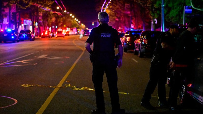 Petugas polisi bekerja di tempat kejadian perkara, sementara jasad korban tergeletak di tanah, setelah sebuah kendaraan melaju ke arah kerumunan saat pesta blok Lapu Lapu di Vancouver, Kanada, Sabtu (26/4/2025). (REUTERS/Chris Helgren)