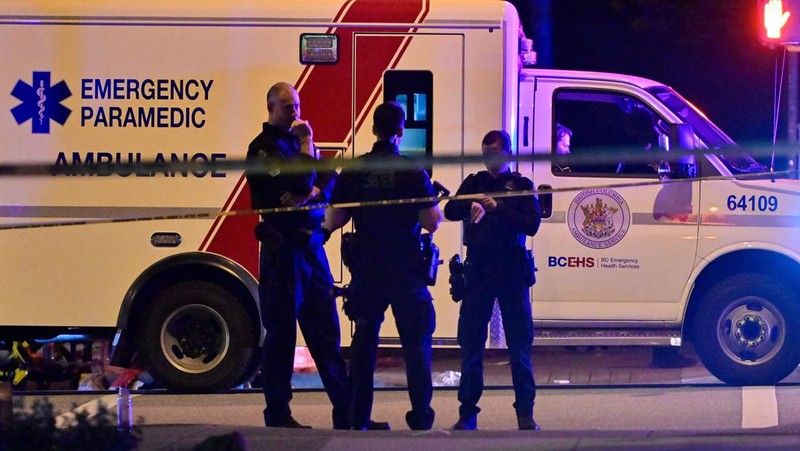 Petugas polisi bekerja di tempat kejadian perkara, sementara jasad korban tergeletak di tanah, setelah sebuah kendaraan melaju ke arah kerumunan saat pesta blok Lapu Lapu di Vancouver, Kanada, Sabtu (26/4/2025). (REUTERS/Chris Helgren)