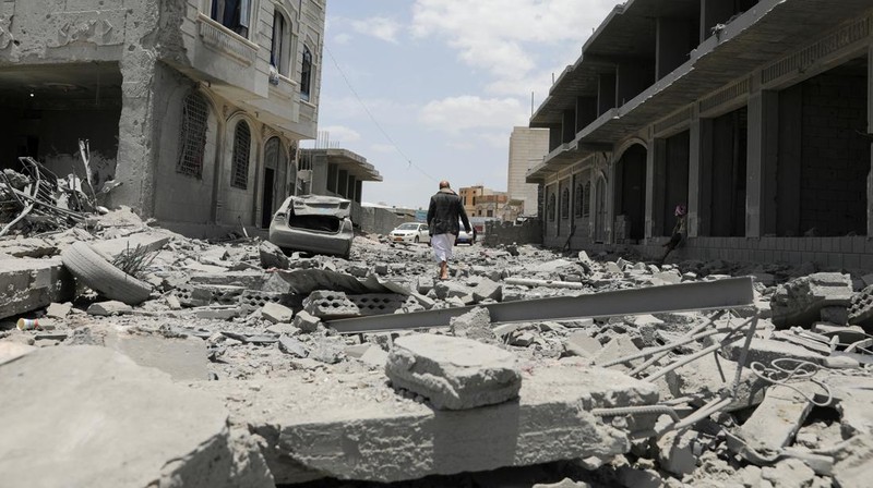 Warga berdiri pada di dekat mobil yang rusak pada lokasi serangan udara AS di Sanaa, Yaman, Minggu (27/4/2025). (REUTERS/Khaled Abdullah)