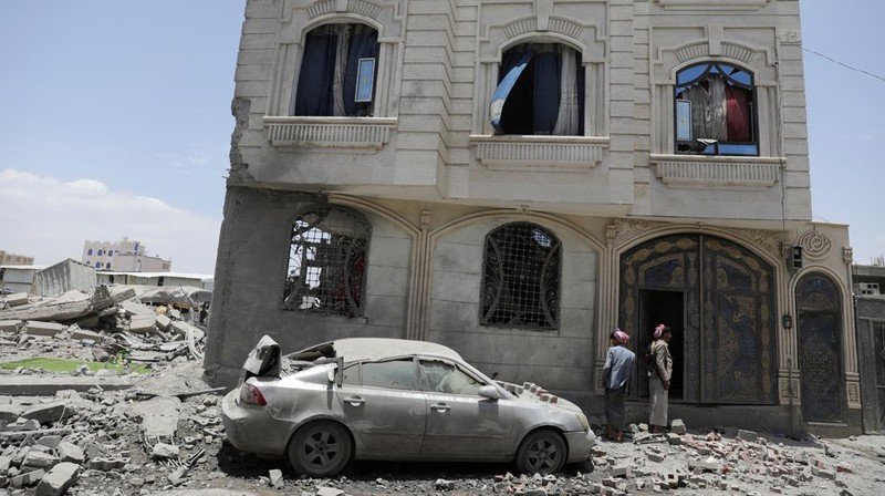 Warga berdiri pada di dekat mobil yang rusak pada lokasi serangan udara AS di Sanaa, Yaman, Minggu (27/4/2025). (REUTERS/Khaled Abdullah)