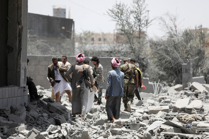 Warga berdiri pada di dekat mobil yang rusak pada lokasi serangan udara AS di Sanaa, Yaman, Minggu (27/4/2025). (REUTERS/Khaled Abdullah)