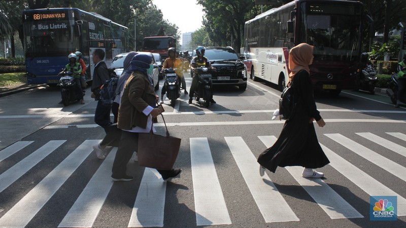 Sejumlah Aparatur Sipil Negara (ASN) berjalan usai naik transportasi umum di kawasan Balai Kota, Jakarta Pusat, pada Rabu (30/4/2025). (CNBC Indonesia/Muhammad Sabki)