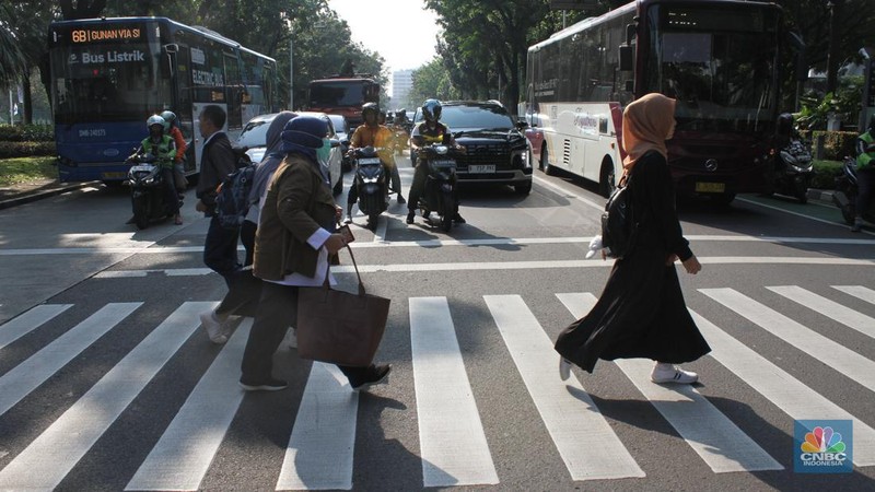 Sejumlah Aparatur Sipil Negara (ASN) berjalan usai naik transportasi umum di kawasan Balai Kota, Jakarta Pusat, pada Rabu (30/4/2025). (CNBC Indonesia/Muhammad Sabki)