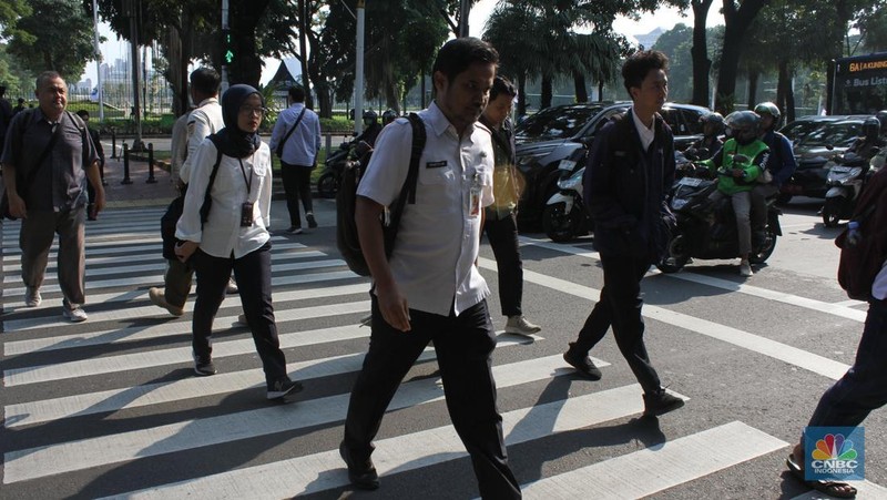 Sejumlah Aparatur Sipil Negara (ASN) berjalan usai naik transportasi umum di kawasan Balai Kota, Jakarta Pusat, pada Rabu (30/4/2025). (CNBC Indonesia/Muhammad Sabki)
