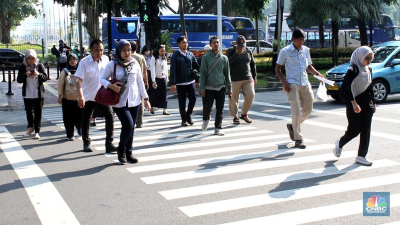 Sejumlah Aparatur Sipil Negara (ASN) berjalan usai naik transportasi umum di kawasan Balai Kota, Jakarta Pusat, pada Rabu (30/4/2025). (CNBC Indonesia/Muhammad Sabki)