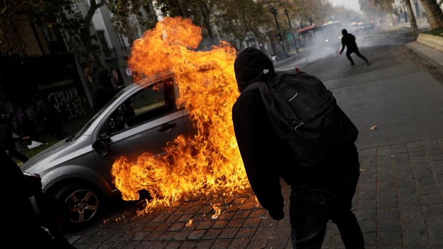 Orang-orang berdiri di samping mobil yang terbakar, selama unjuk rasa May Day, di Santiago, Cile, 1 Mei 2025. Orang-orang berdiri di samping mobil yang terbakar, selama unjuk rasa May Day, di Santiago, Cile, 1 Mei 2025. (REUTERS/Juan Gonzalez)