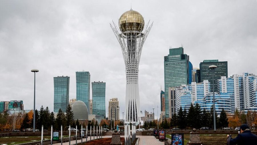 Pejalan kaki berjalan di dekat menara Baiterek (Bayterek) di bawah langit berawan, di Astana, pada 30 Oktober 2023. (Photo by Ludovic MARIN / AFP/File Foto)