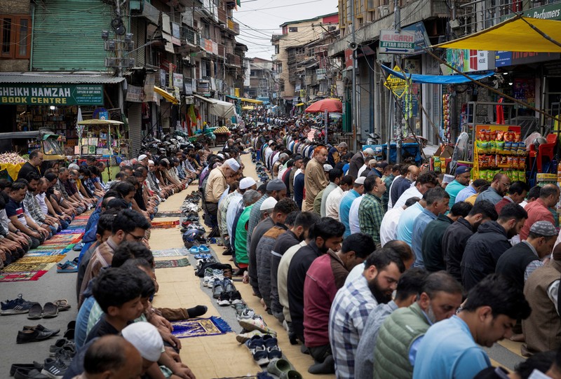 Umat ​​Muslim Kashmir melaksanakan salat Jumat di jalan sementara petugas keamanan berjaga di Srinagar, 2 Mei 2025. (REUTERS/Adnan Abidi)