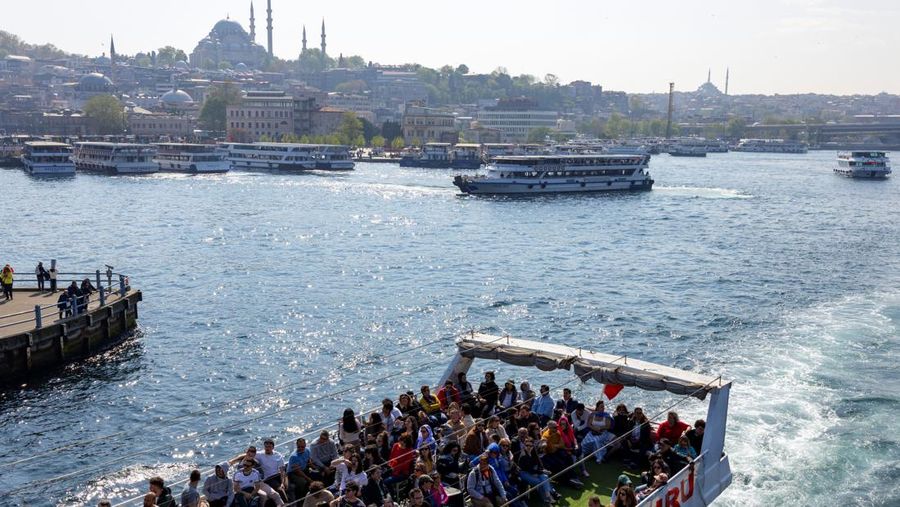 Orang-orang memberi makan burung camar saat mereka berlayar melalui Bosphorus dengan feri di Istanbul, Turki, 23 April 2025. (REUTERS/Umit Bektas)