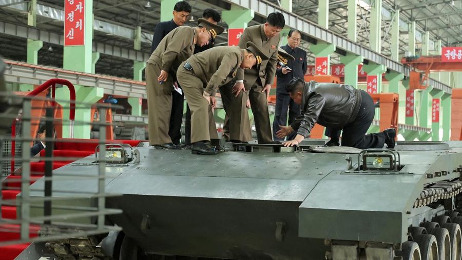 Pemimpin Korea Utara Kim Jong Un berjalan di dekat peluncur rudal bergerak saat ia mengunjungi militer Pemimpin Korea Utara Kim Jong Un mengunjungi pabrik tank. Kim Jong Un memuji kemajuan besar tank-tank yang diproduksi pabrik tersebut. (via REUTERS/KCNA)