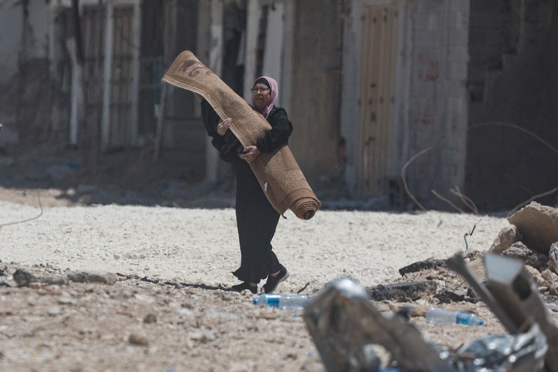 Warga Palestina membawa barang-barang mereka setelah keputusan Israel untuk menghancurkan rumah mereka di kamp Nur Shams, Selasa (6/5/2025). (REUTERS/Raneen Sawafta)