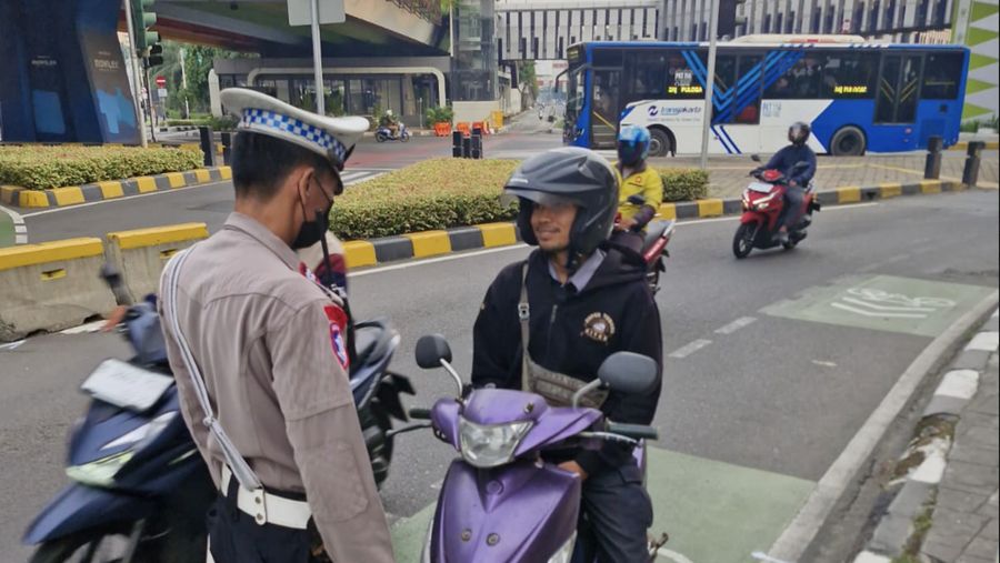 Seorang Polisi menindak seorang pengendara yang melanggar dengan tidak memasang plat nomor. (X/@TMCPoldaMetro)