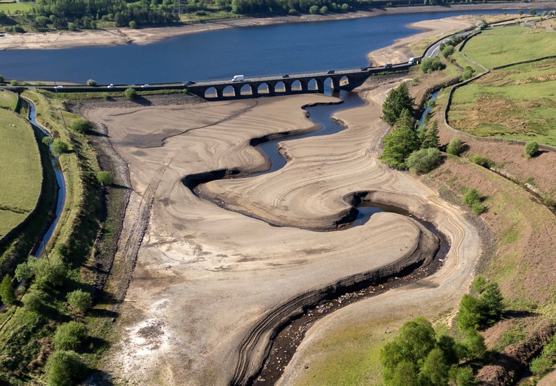 Pemandangan drone menunjukkan kendaraan menggunakan jembatan untuk melewati bagian Waduk Woodhead yang sebagian kering setelah periode panjang tanpa hujan, yang mengakibatkan turunnya permukaan air, dekat Tintwistle, Inggris, 13 Mei 2025. (REUTERS/Phil Noble)
