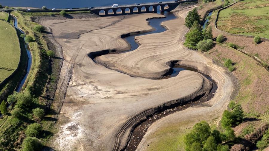 Pemandangan drone menunjukkan kendaraan menggunakan jembatan untuk melewati bagian Waduk Woodhead yang sebagian kering setelah periode panjang tanpa hujan, yang mengakibatkan turunnya permukaan air, dekat Tintwistle, Inggris, 13 Mei 2025. (REUTERS/Phil Noble)