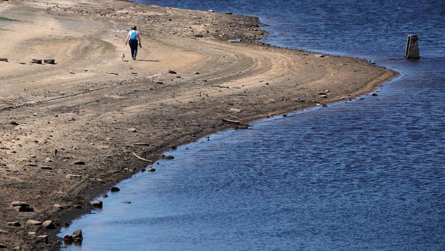 Pemandangan drone menunjukkan kendaraan menggunakan jembatan untuk melewati bagian Waduk Woodhead yang sebagian kering setelah periode panjang tanpa hujan, yang mengakibatkan turunnya permukaan air, dekat Tintwistle, Inggris, 13 Mei 2025. (REUTERS/Phil Noble)