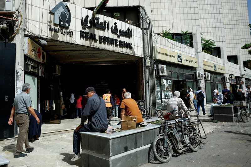 Warga berkumpul di mesin ATM Bank Komersial Suriah untuk menarik uang, setelah Presiden AS Donald Trump mengumumkan bahwa ia akan memerintahkan pencabutan sanksi terhadap Suriah, di Damaskus, Suriah, 14 Mei 2025. REUTERS/Yamam al ShaarREUTERS/Yamam al Shaar