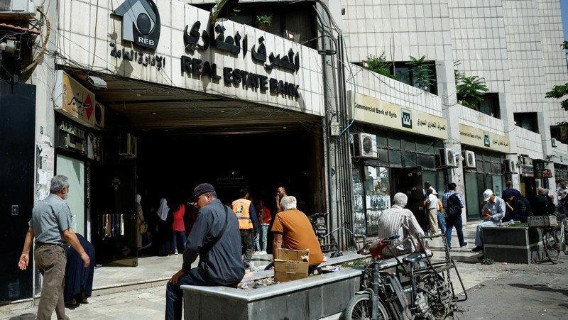 Warga berkumpul di mesin ATM Bank Komersial Suriah untuk menarik uang, setelah Presiden AS Donald Trump mengumumkan bahwa ia akan memerintahkan pencabutan sanksi terhadap Suriah, di Damaskus, Suriah, 14 Mei 2025. REUTERS/Yamam al ShaarREUTERS/Yamam al Shaar