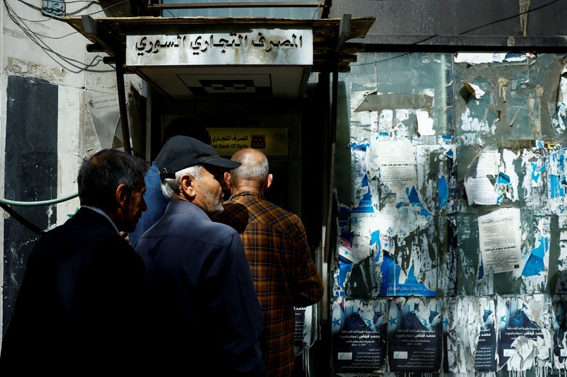 Warga berkumpul di mesin ATM Bank Komersial Suriah untuk menarik uang, setelah Presiden AS Donald Trump mengumumkan bahwa ia akan memerintahkan pencabutan sanksi terhadap Suriah, di Damaskus, Suriah, 14 Mei 2025. REUTERS/Yamam al ShaarREUTERS/Yamam al Shaar