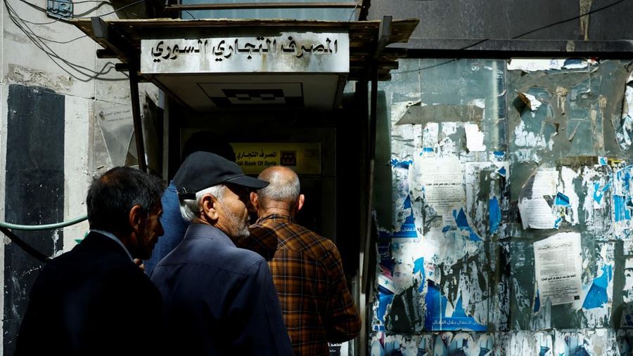 Warga berkumpul di mesin ATM Bank Komersial Suriah untuk menarik uang, setelah Presiden AS Donald Trump mengumumkan bahwa ia akan memerintahkan pencabutan sanksi terhadap Suriah, di Damaskus, Suriah, 14 Mei 2025. REUTERS/Yamam al ShaarREUTERS/Yamam al Shaar
