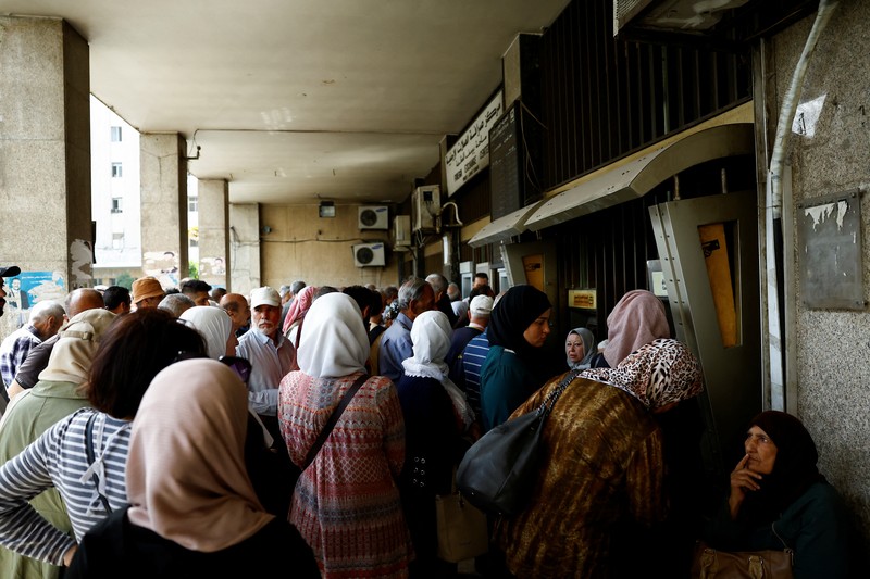 Warga berkumpul di mesin ATM Bank Komersial Suriah untuk menarik uang, setelah Presiden AS Donald Trump mengumumkan bahwa ia akan memerintahkan pencabutan sanksi terhadap Suriah, di Damaskus, Suriah, 14 Mei 2025. REUTERS/Yamam al ShaarREUTERS/Yamam al Shaar