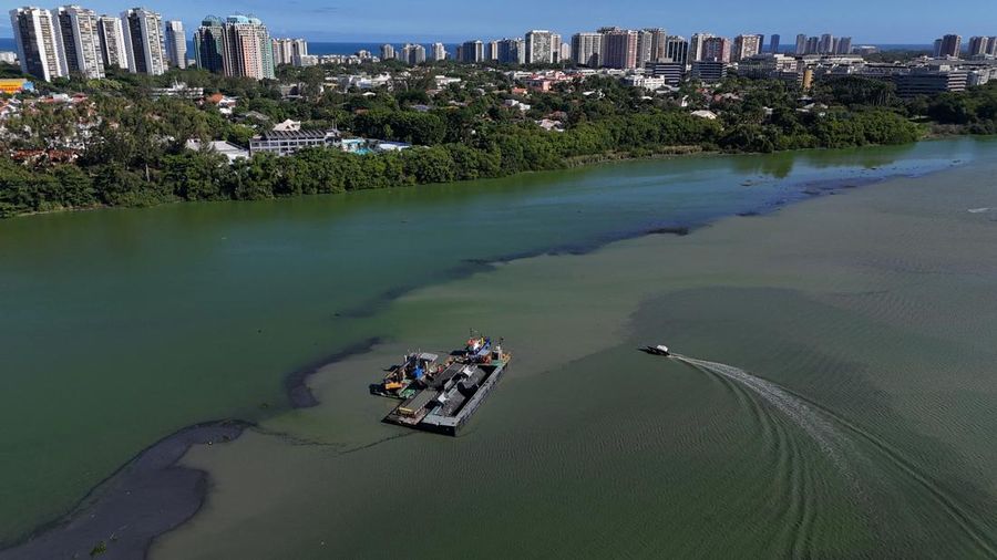 Pemandangan drone menunjukkan tongkang bekerja mengeruk laguna Barra dan Jacarepagua, saat air dari laguna tersebut menodai laut menjadi hijau di lepas pantai Barra da Tijuca, menurut media lokal, di Rio de Janeiro, Brasil, 15 Mei 2025. (REUTERS/Ricardo Moraes)
